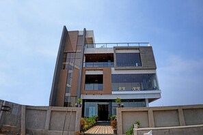 A modern multi-story building with a glass facade, a visible staircase leading to the entrance, and a flat roof. - Hotel JK PARADISE (Chirala)