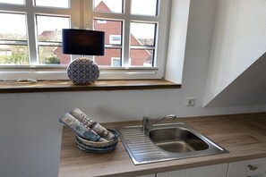 A kitchen with a window, a sink, and a lamp on the windowsill. - Holiday apartment with 1 bedroom (Baltrum)