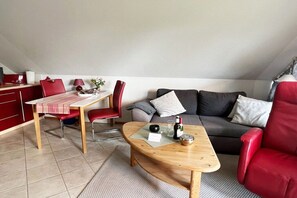 En kompakt opholdsstue med spisebord, røde stole, sofa og sofabord.