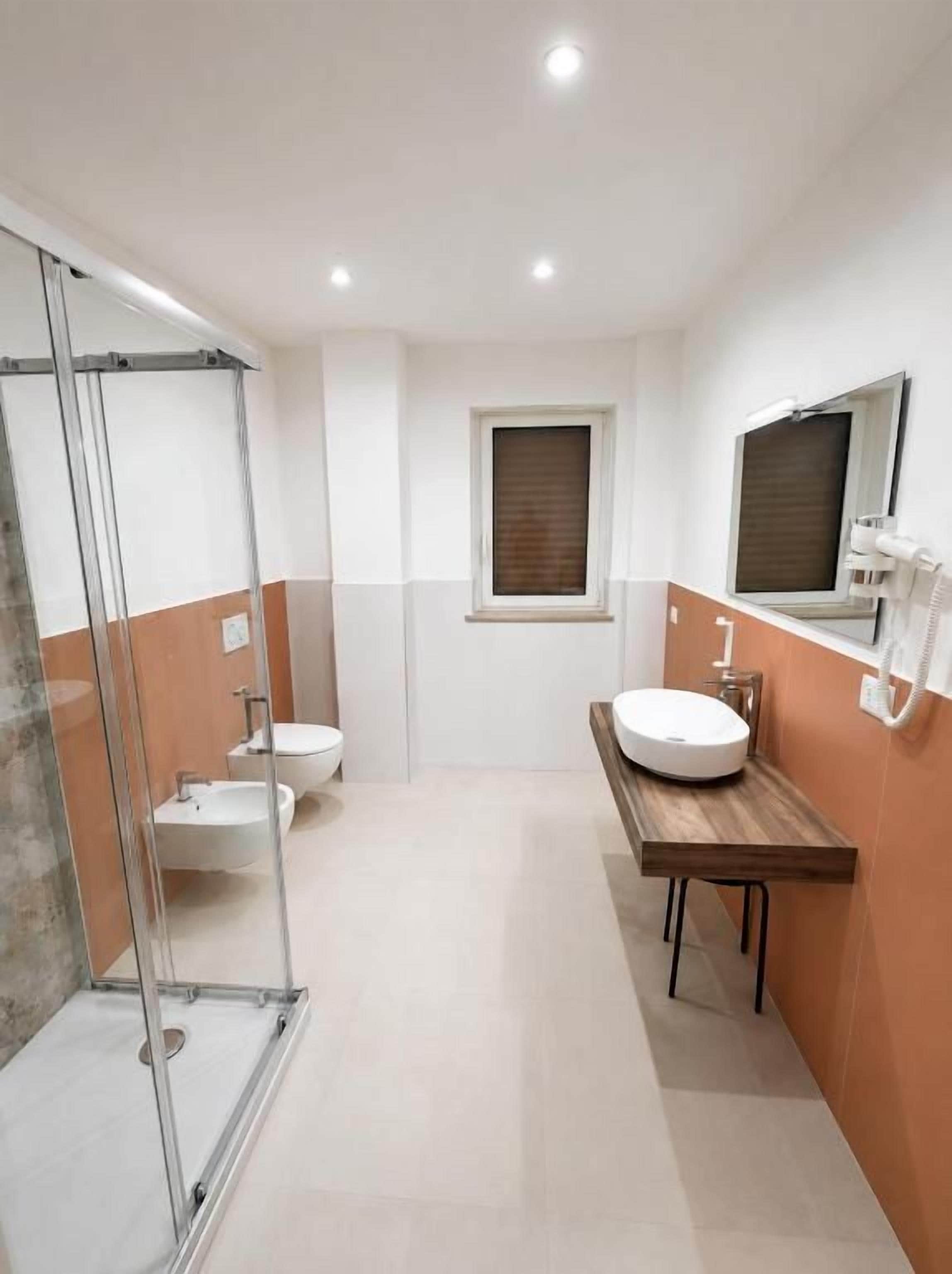 Un bagno moderno con box doccia in vetro, un water, un lavabo e uno specchio.
