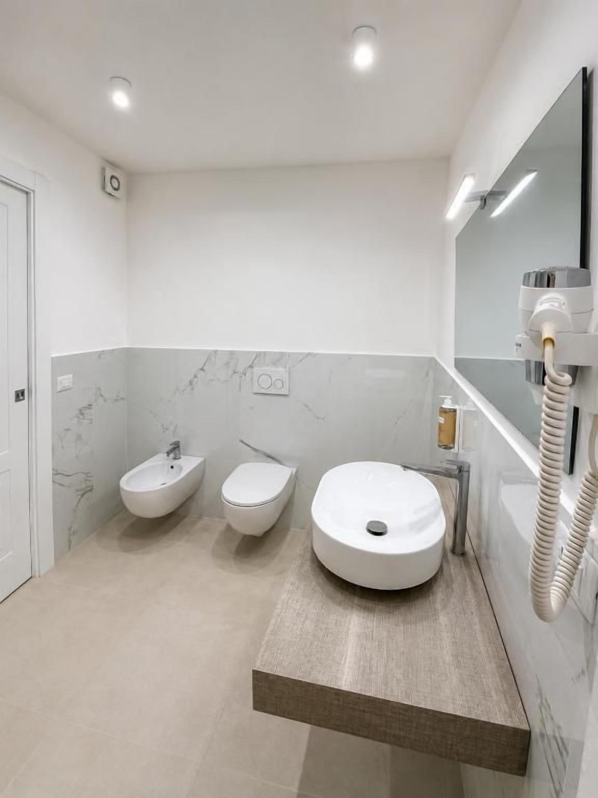 Un bagno moderno con un lavandino capiente, un bidet e uno specchio.