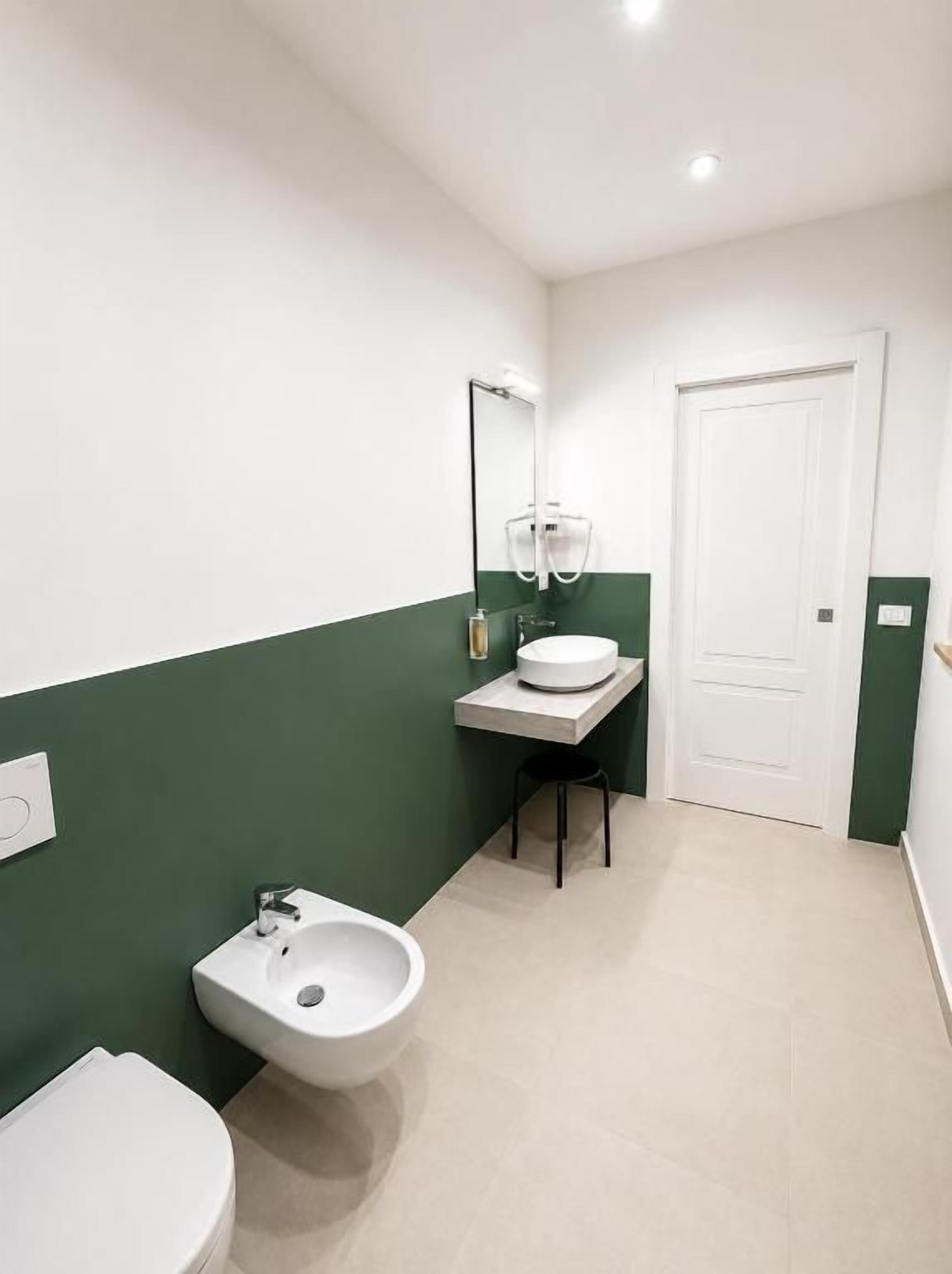 A bathroom with a bidet, toilet, and sink.