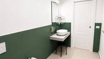 A bathroom with a bidet, toilet, and sink.