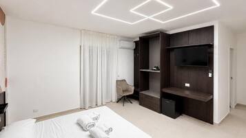 Ein modernes Hotelzimmer mit einem großen Bett, einem Flachbildfernseher, Einbauschränken und einem Sessel.