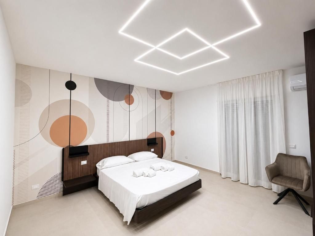 Ein modernes Hotelzimmer mit einem Bett, einem Sessel und einer Wand mit abstrakten Mustern.