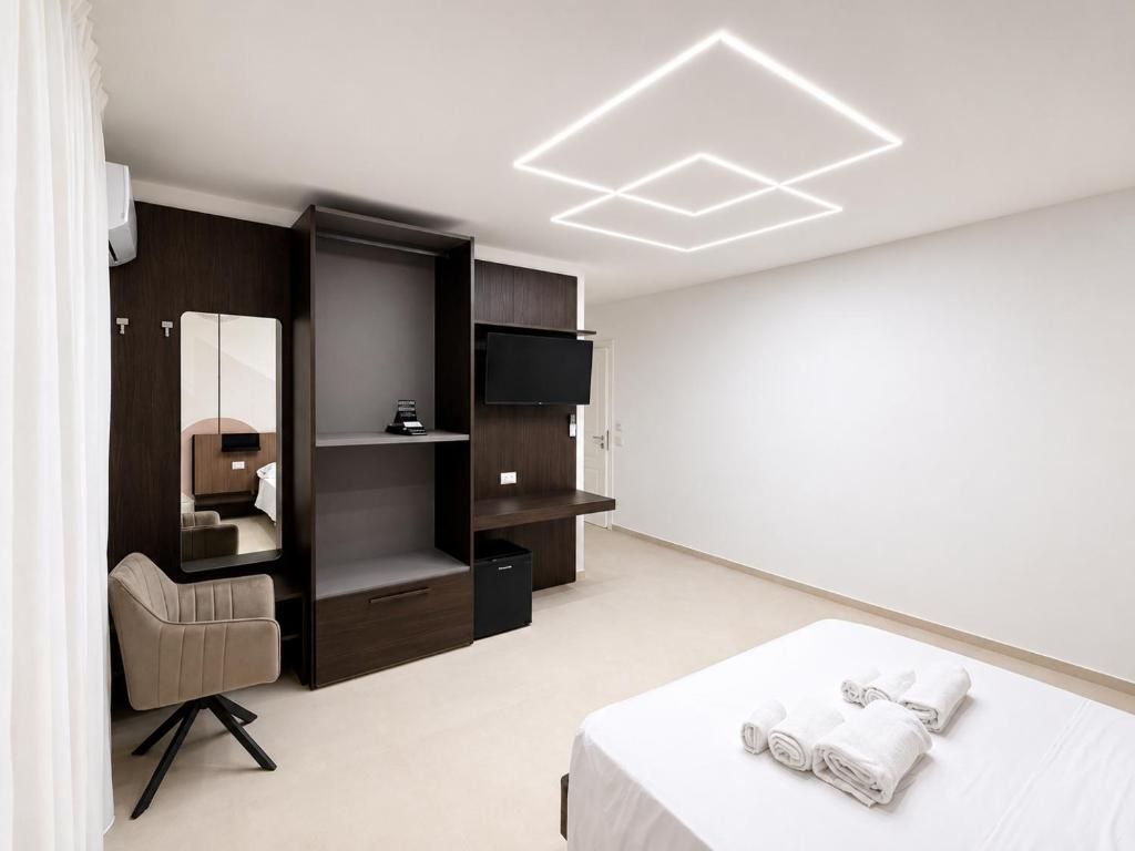 Ein modernes Hotelzimmer mit Bett, Schreibtisch, Stuhl, Kleiderschrank und Flachbildfernseher.