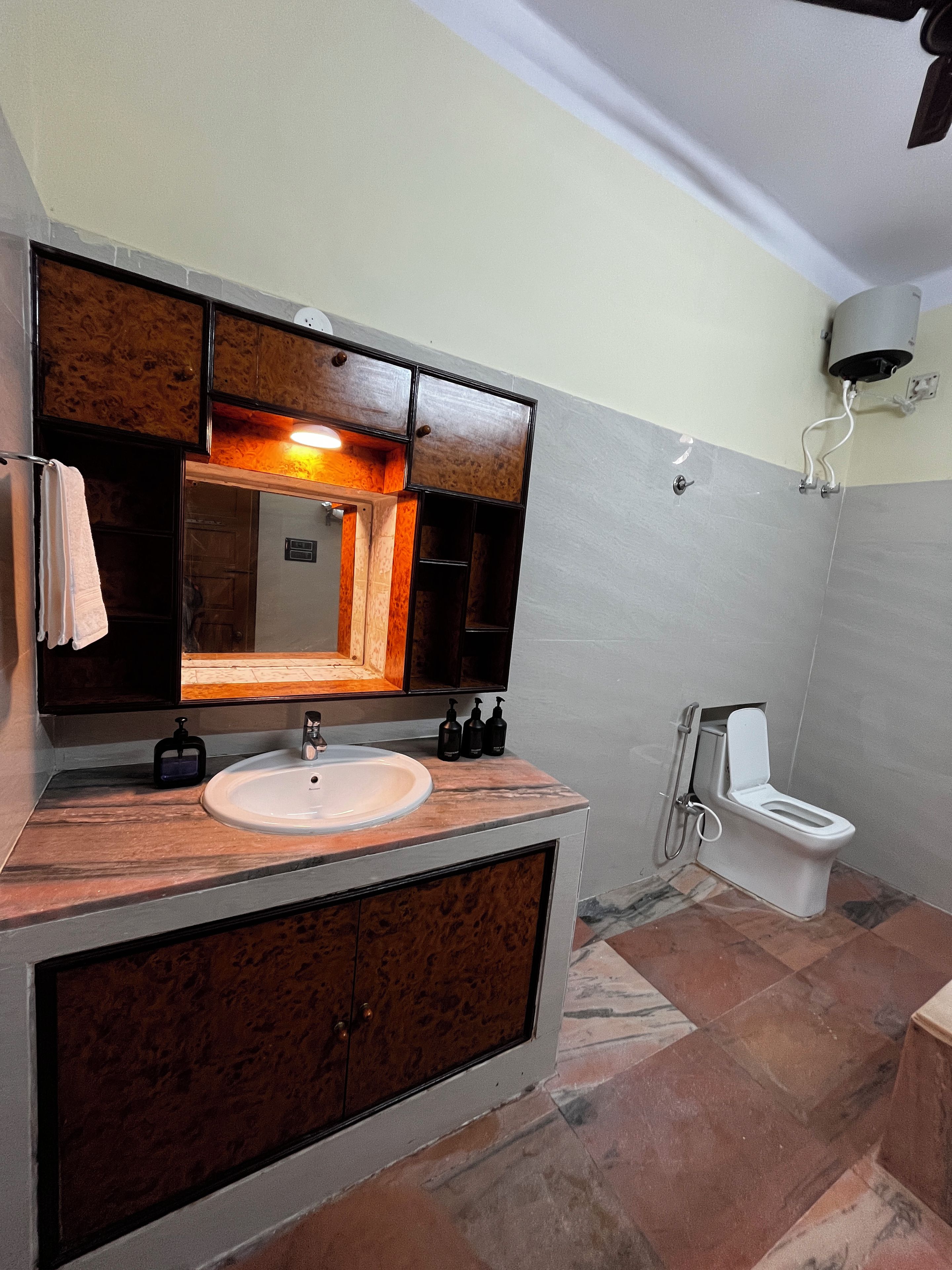 A bathroom with a wooden vanity, a sink, a mirror, and a toilet.