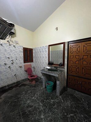 Un baño con inodoro rosa, un lavamanos con espejo y un armario de madera con diseños geométricos.