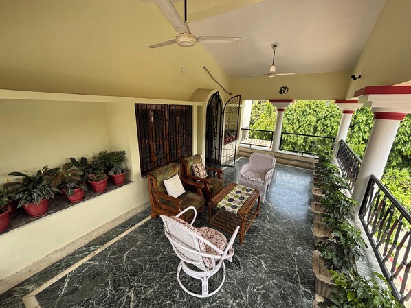 Un balcon abrité, doté d’un ventilateur de plafond, de plantes en pot et de mobilier d’extérieur.
