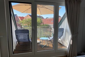 Ein Zimmer mit einer Schiebetür, die auf eine Außenpatio mit Tisch und Stühlen führt.