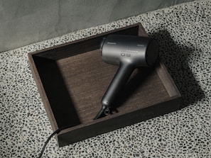 A Panasonic hair dryer in a wooden tray on a terrazzo floor. - Toune Machiya House (Shimogyo-ku)