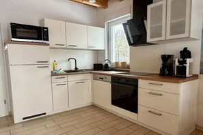 A compact kitchen with white cabinetry, a microwave, a kettle, and a coffee maker. - Holiday home with 3 bedrooms (Plau am See)