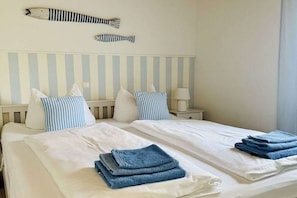A hotel room with two beds, striped headboards, and a fish-shaped wall decoration. - Holiday home with 3 bedrooms (Plau am See)