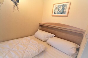 A small, single-bed room with a wooden headboard, a framed picture on the wall, and a quilted bedspread. - Lord Nelson, 2nd floor (Cuxhaven)