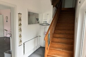 A wooden staircase with a handrail, a radiator, and a window with a view of the outside. - Bruns holiday apartment (Ihlow)