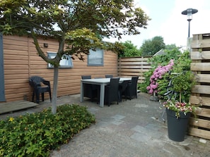 A patio area with a table and chairs, a small tree, and a flower pot. - Chalet Special T32 (Makkum)