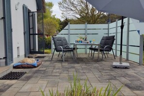 An outdoor patio with a table and chairs, a covered area, and a white fence. - Holiday home with 2 bedrooms (Glowe - Insel Rügen)