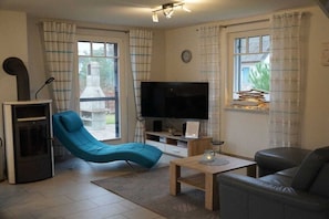 A living room with a television, a sofa, a chair, and a small table. - Holiday home with 2 bedrooms (Glowe - Insel Rügen)