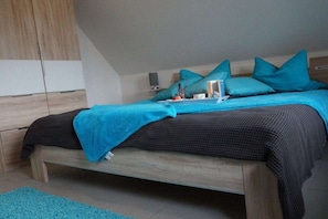 A bedroom with a bed, a nightstand, a wall-mounted shelf, and a wardrobe. - Holiday home with 2 bedrooms (Glowe - Insel Rügen)