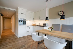A modern kitchen with white cabinets, a wooden countertop, and pendant lighting. - wat"nmeer im Achthus auf Juist (Juist)