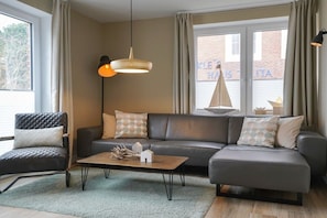 A modern living room with a leather sofa, a coffee table, and a pendant light. - wat"nmeer im Achthus auf Juist (Juist)