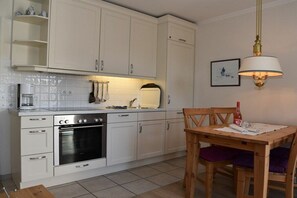 Een keuken met witte kastjes, een houten tafel en een hanglamp.
