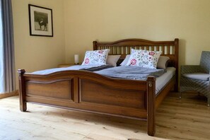 A wooden bed with a headboard, two pillows with floral patterns, and a chair with a patterned cover. - ||-----------------------Old schoolhouse-----------------------|| (Bergen)