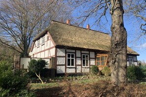 A traditional half-timbered house with a thatched roof, surrounded by trees and a stone wall. - ||-----------------------Old schoolhouse-----------------------|| (Bergen)