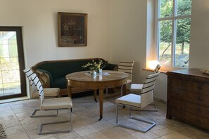 A dining area with a round wooden table, two white chairs, a green sofa, and a wooden cabinet. - ||-----------------------Old schoolhouse-----------------------|| (Bergen)