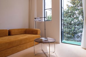 Habitación con sofá, una mesita, una lámpara de pie y vistas a zonas verdes.