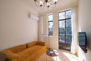 A modern living room with a sofa, a small table, a floor lamp, and a TV mounted on the wall. - Book&Bed-People's Sq. Changzheng Hosp. (Huangpu District)