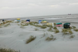 Una playa con dunas de arena y sillas de playa.