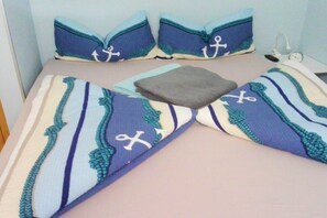 A bed with striped bedding and two pillows with anchor designs. - 10 at the new lighthouse (Borkum)