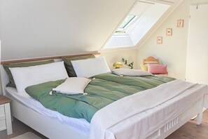 A single bed with a green and white duvet, a wooden headboard, and a skylight above. - Holiday apartment with 1 bedroom (Borkum)
