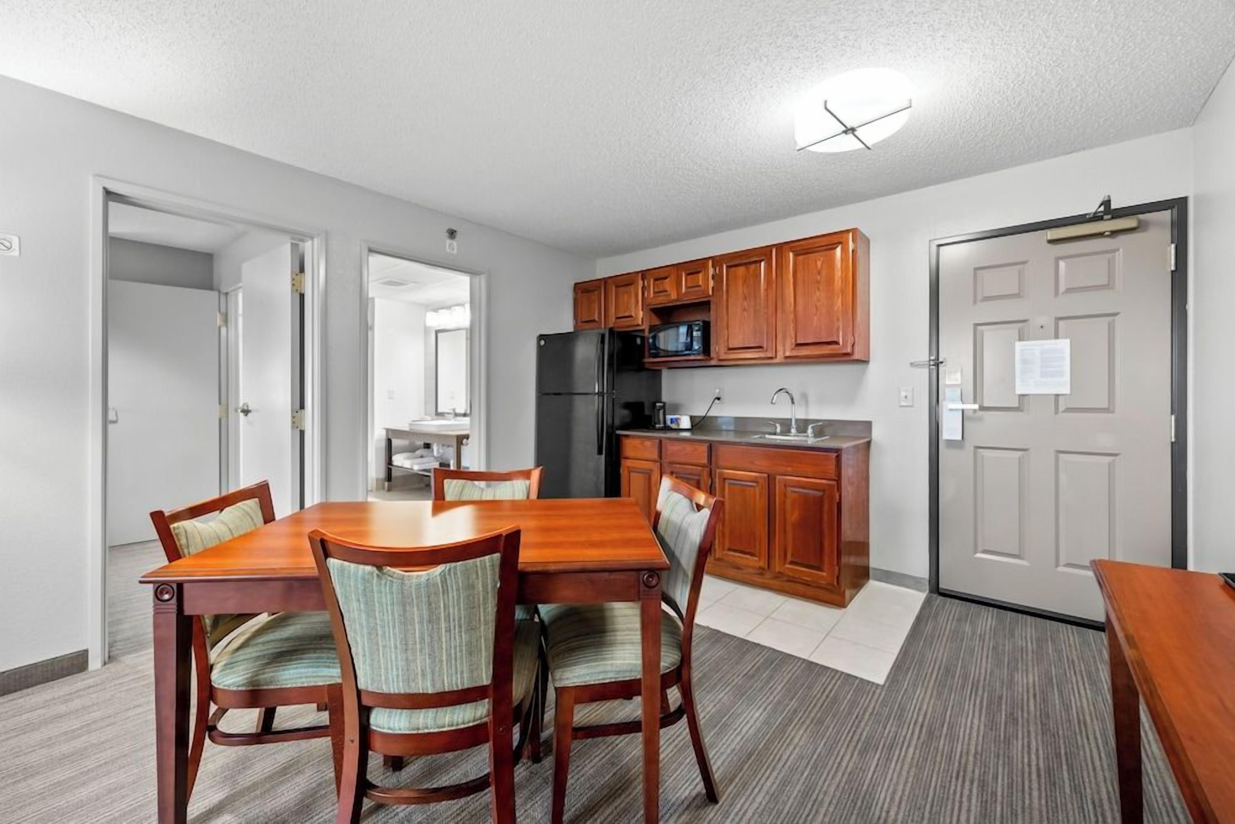 A compact kitchen with wooden cabinets, a refrigerator, and a microwave.