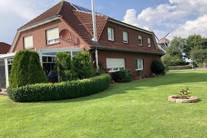 A two-story house with a sloped roof, a satellite dish, and a garage. - Holiday apartment with 2 bedrooms (Dornumersiel\/ Westerbur)