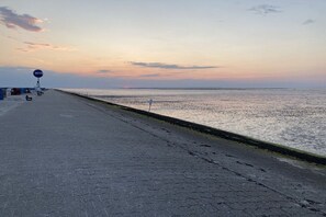 Ein Küstenweg mit einem Schild, das auf eine Aussichtsplattform hinweist, der zum Meer führt.