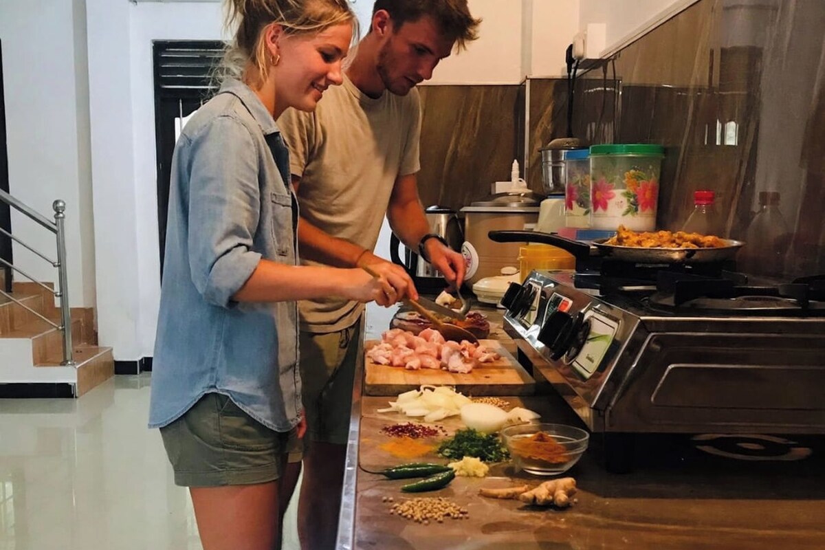 A modern kitchen with stainless steel appliances, a wooden countertop, and a person preparing food.