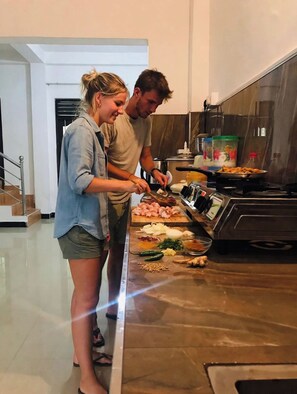 A modern kitchen with stainless steel appliances, a wooden countertop, and a person preparing food. - Vihansha Guesthouse Weligama  (Weligama)