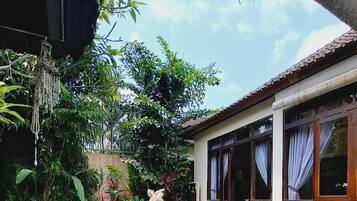 A swimming pool with a tiled edge, surrounded by greenery and a building with windows.