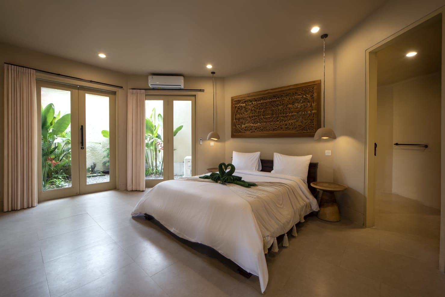 Un dormitorio amplio con una cama grande, ventilador de techo y vistas al exterior.