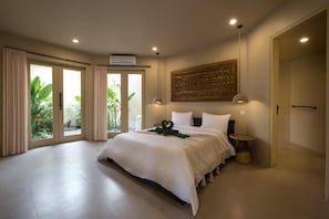 A spacious bedroom with a large bed, a ceiling fan, and a view of greenery outside.