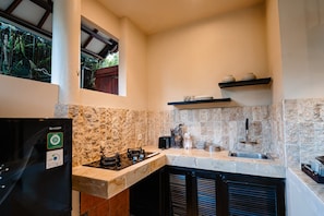 A compact kitchen with a gas stove, a sink, and a refrigerator. - Gajah Biru Ubud (Ubud,Gianyar)