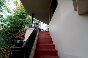 A staircase with red steps leading up to a balcony, surrounded by greenery. - Gajah Biru Ubud (Ubud,Gianyar)