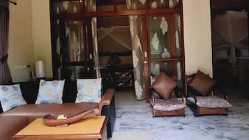 Un amplio salón con techo alto, un conjunto de sofás, una mesa de centro y vistas a través de un gran ventanal.