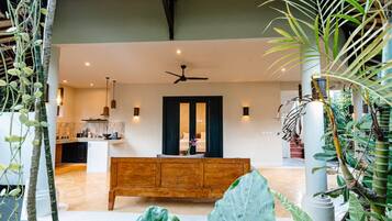 A modern interior with a wooden bench, a ceiling fan, and a view into a bedroom.