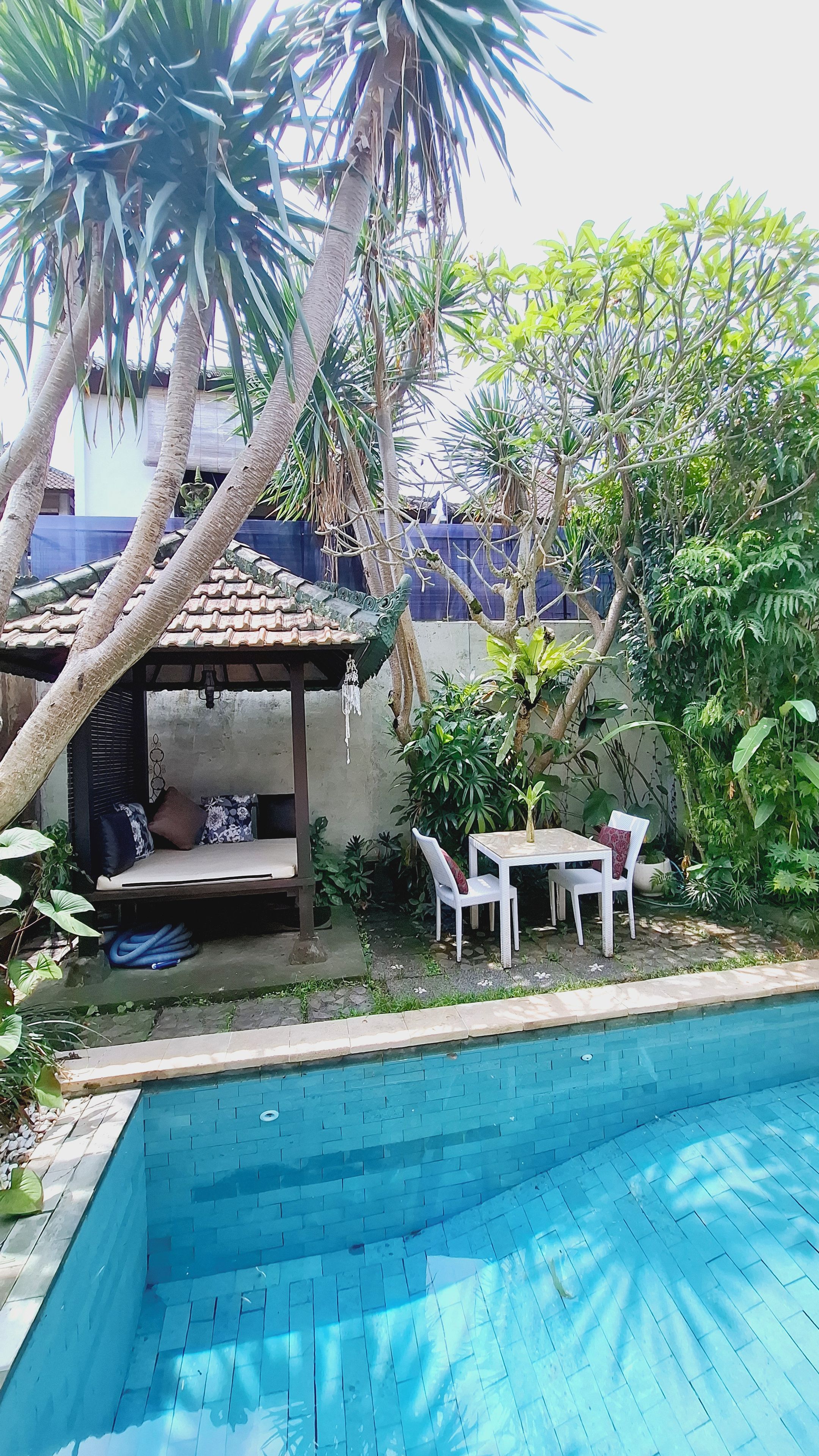 Un área de piscina con una zona de estar cubierta y una mesa pequeña.