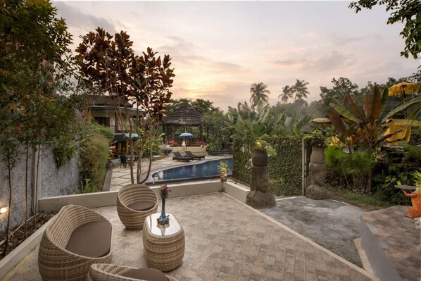 A pool area with lounge chairs, a gazebo, and tropical plants.