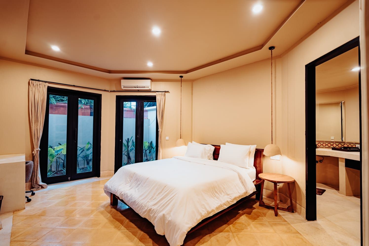 Habitación de hotel con una cama grande, una mesita de noche, un espejo y vistas al exterior.
