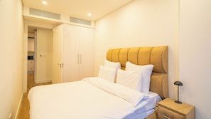 A bedroom with a bed, bedside table, and a wardrobe. - The Illovo Residence | Luxury 1-Bedroom Apartment (Sandton)